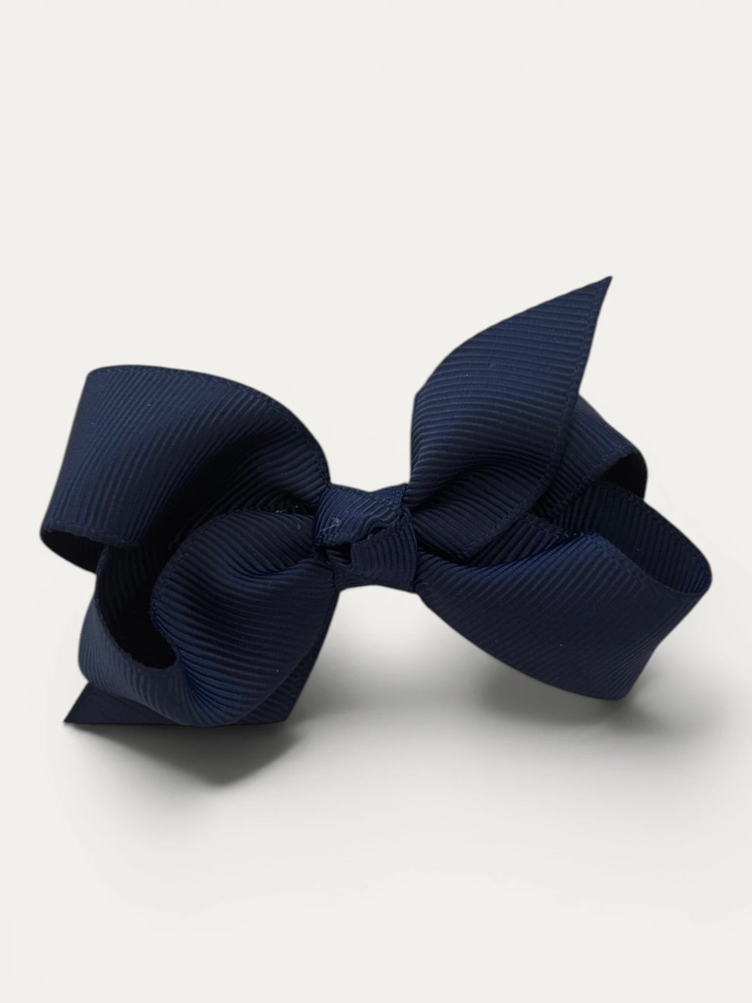 Fine grosgrain bow hair clip for girls; elegant texture, feminine silhouette, made in Spain and shipped from Switzerland.