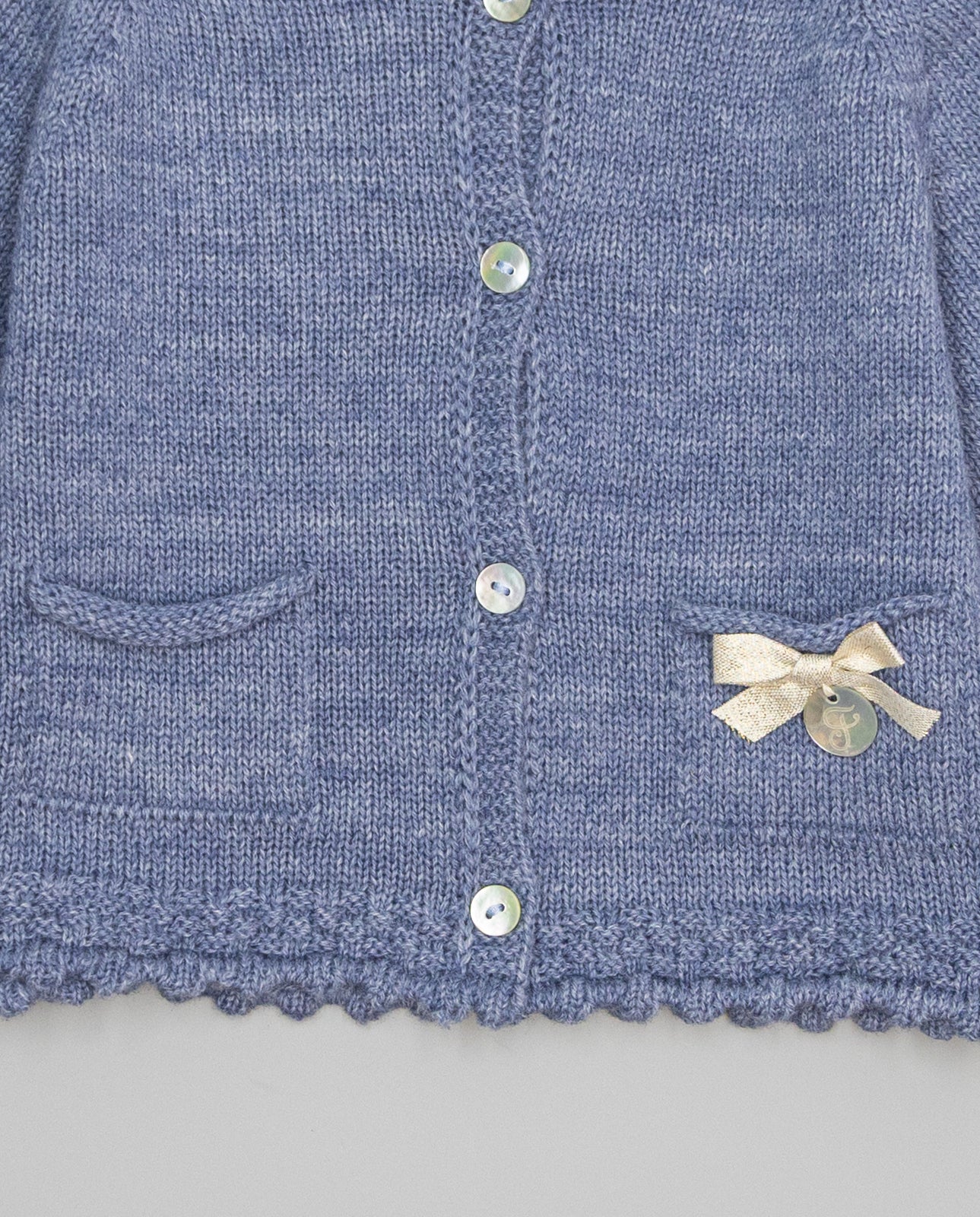 Blue knitted kids cardigan with metallic bow and pearl initial button